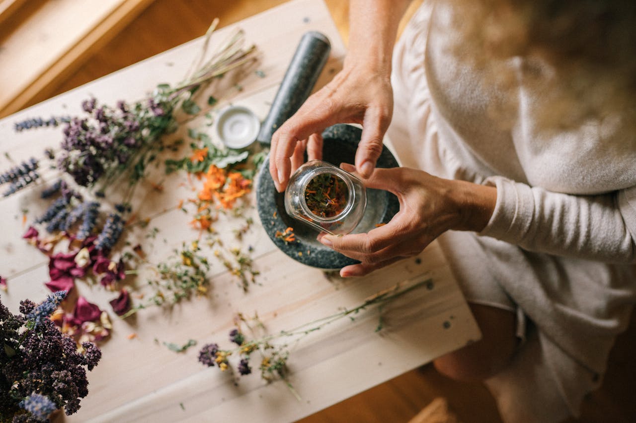 Hands preparing dried flowers and herbs in a mortar. Ideal for holistic and wellness themes.